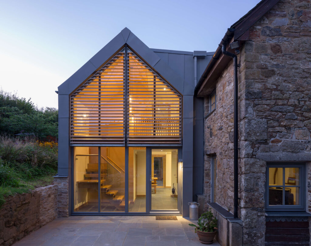 Glazed gable with louvres at dusk. Lutterburn award winning barn conversion. Threshold Architects Passivhaus Tim Offer South Devon South Hams